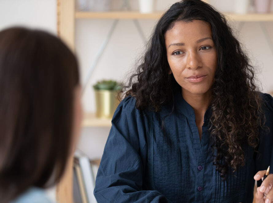 Two women sat at a desk, talking