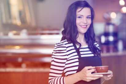 Image of a female cofee shop worker smiling at the camera