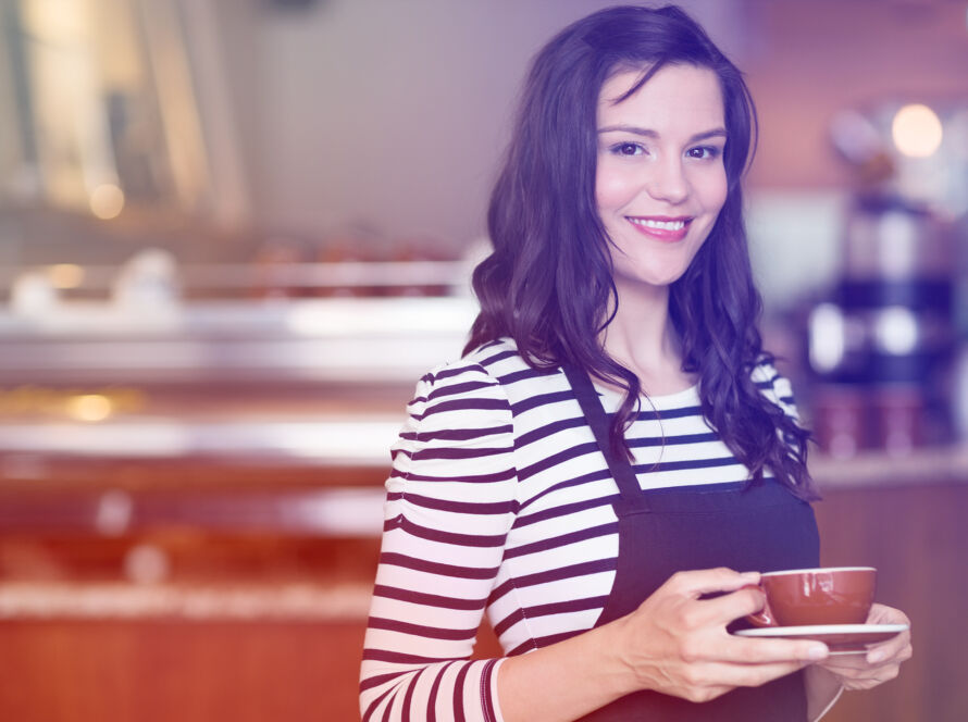 Image of a female cofee shop worker smiling at the camera