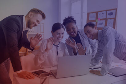 Group of people huddled around a laptop waving.