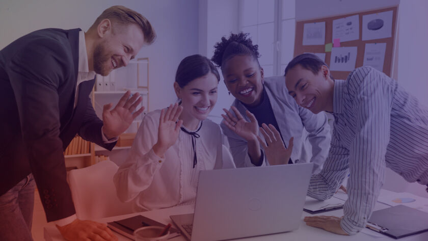 Group of people huddled around a laptop waving.