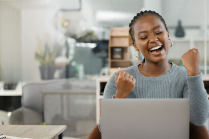 Woman celebrating whilst looking at laptop