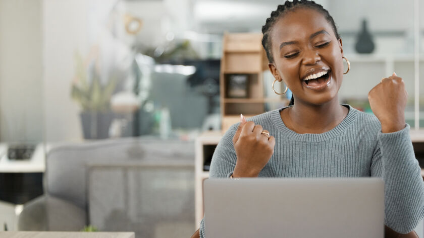 Woman celebrating whilst looking at laptop