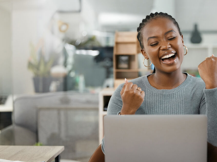 Woman celebrating whilst looking at laptop